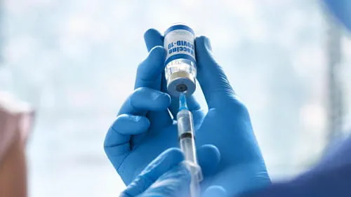 医疗专业人员用注射器从小瓶中取出。
